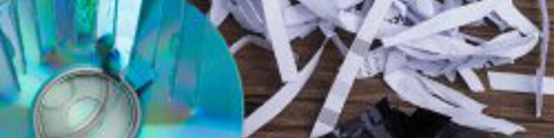 AdobeStock_76386706 Kaputte CDs und geschreddertes Papier liegen auf einer Fläche