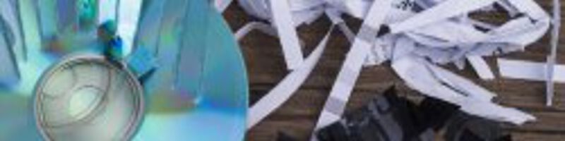 Aktenvernichtung Kaputte CDs und geschreddertes Papier liegen auf einer Fläche