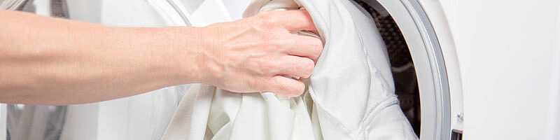 Foto: Hand befüllt Waschmaschine mit Weißwäsche