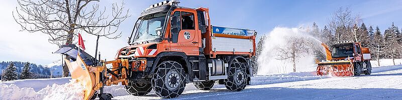 Winterdienstfahrzeuge in verschneiter Umgebung bei der Arbeit