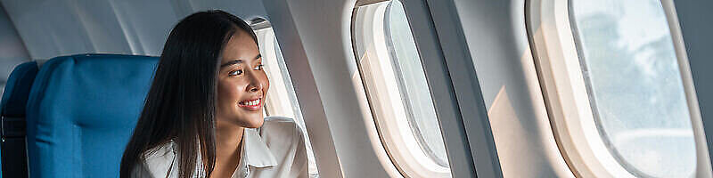 AdobeStock_586235187 Frau im Flugzeug schaut aus dem Fesnter